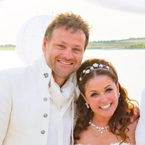 strahlende Gesichter vom Brautpaar in Weiß vor dem Meer