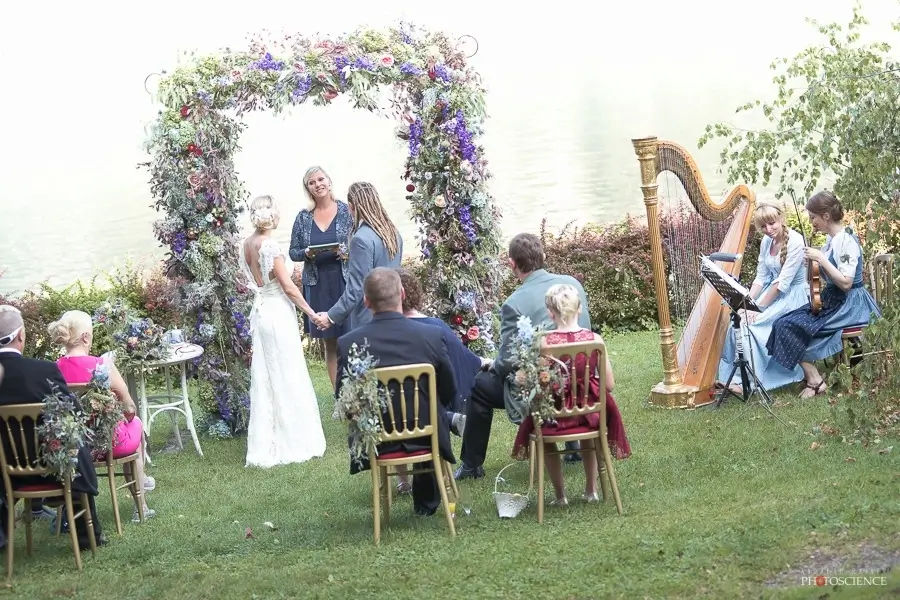 Freie Trauung im Grünen, Brautpaar steht mit Heike Schönbacher unter Blumenbogen