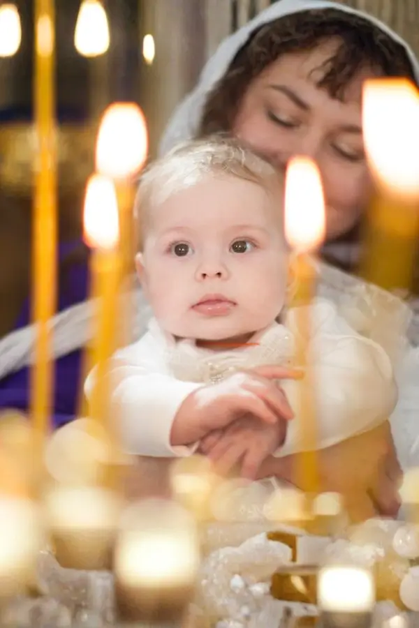 Baby bei freier Taufe mit Patin hinter mehreren Kerzen - interessierter Blick