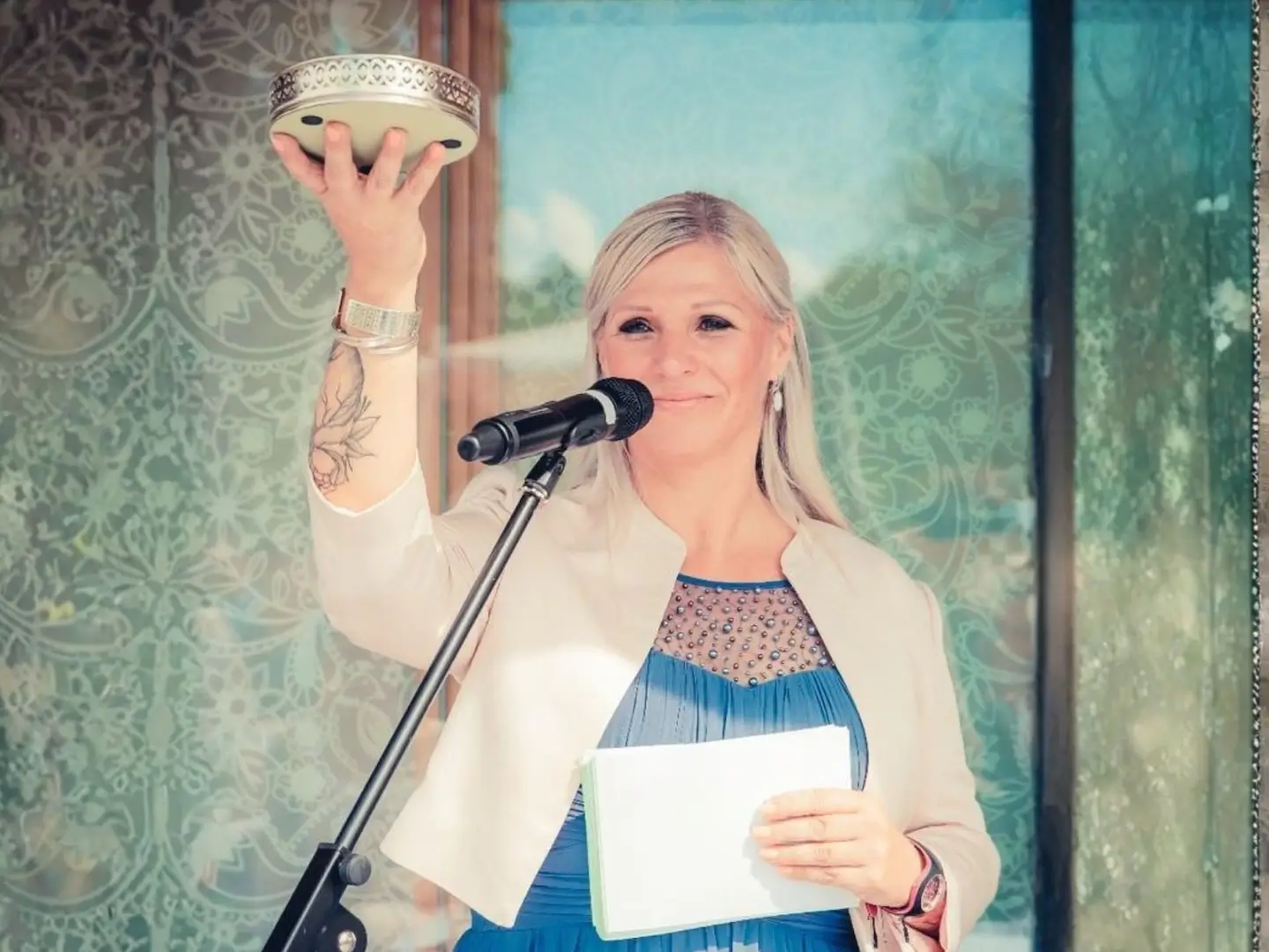 Heike Schönbacher mit goldener Schale in hoch erhobener Hand vor dem Mikrofon bei freier Taufe in der Steiermark