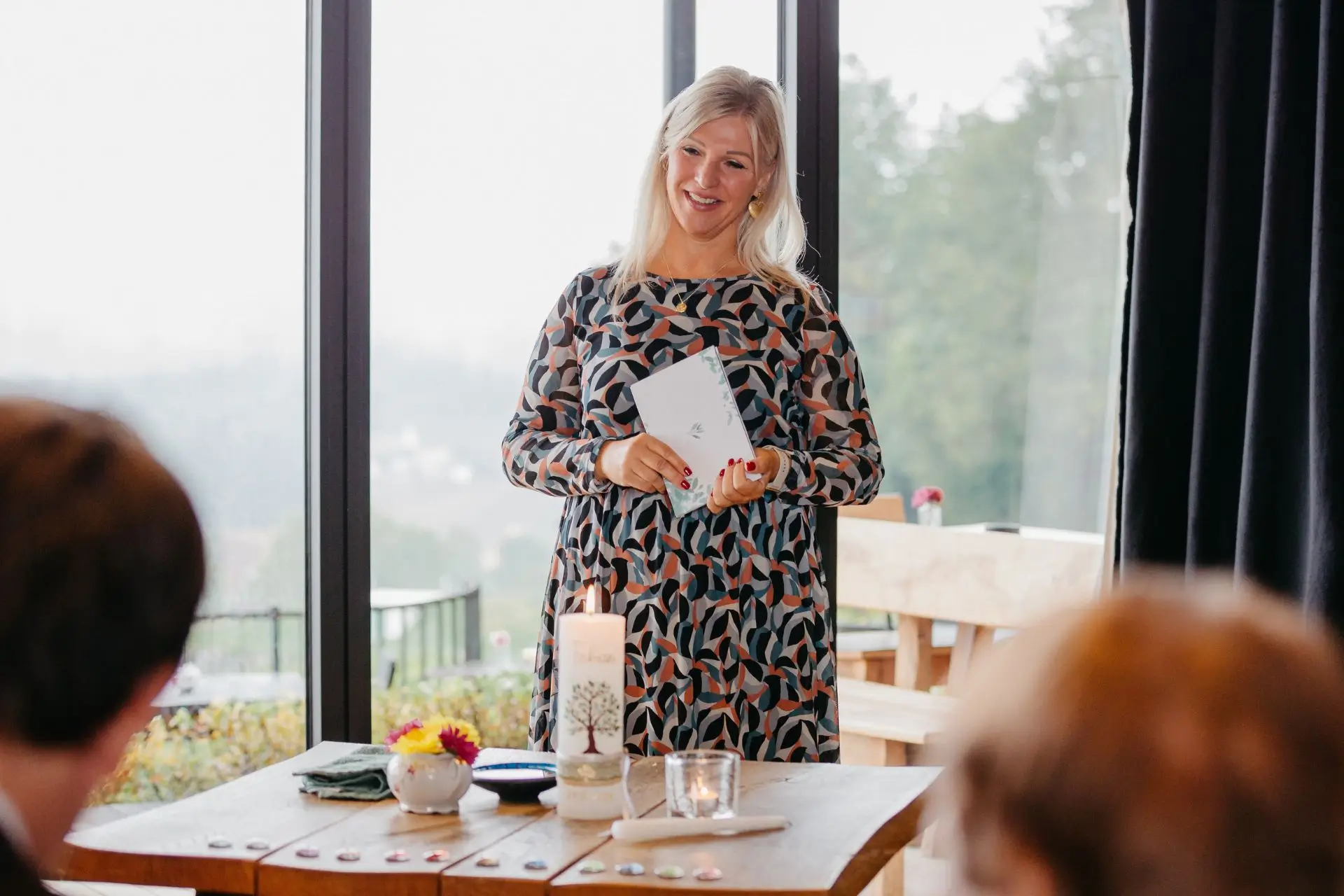Freie Taufe HerrgottHö Stainz mit Rednerin Heike Schönbacher - steht vor Tisch mit brennender Kerze und spricht zu Eltern