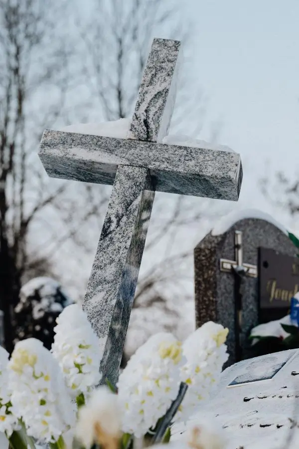 Grab bei Grabrede von Heike Schönbacher, weiße Blumen im Vordergrund mit Kreuz aus Stein