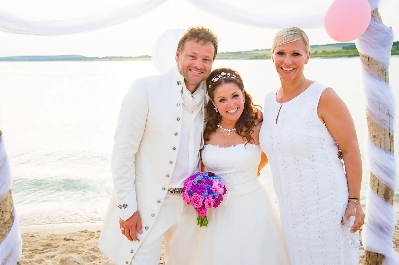Heike Schönbacher neben Brautpaar zu dritt lachend am Meer