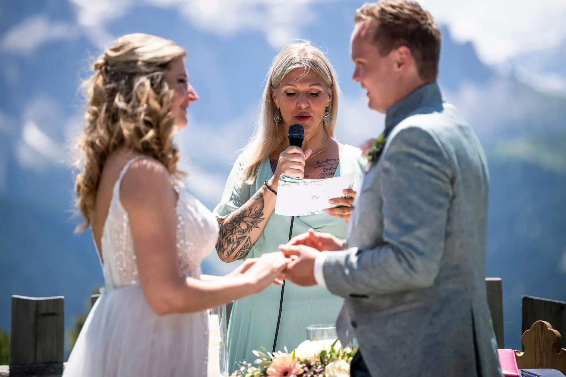 Heike Schönbacher spricht vor Brautpaar mit Mikrofon auf Terrasse schwarz-weiß