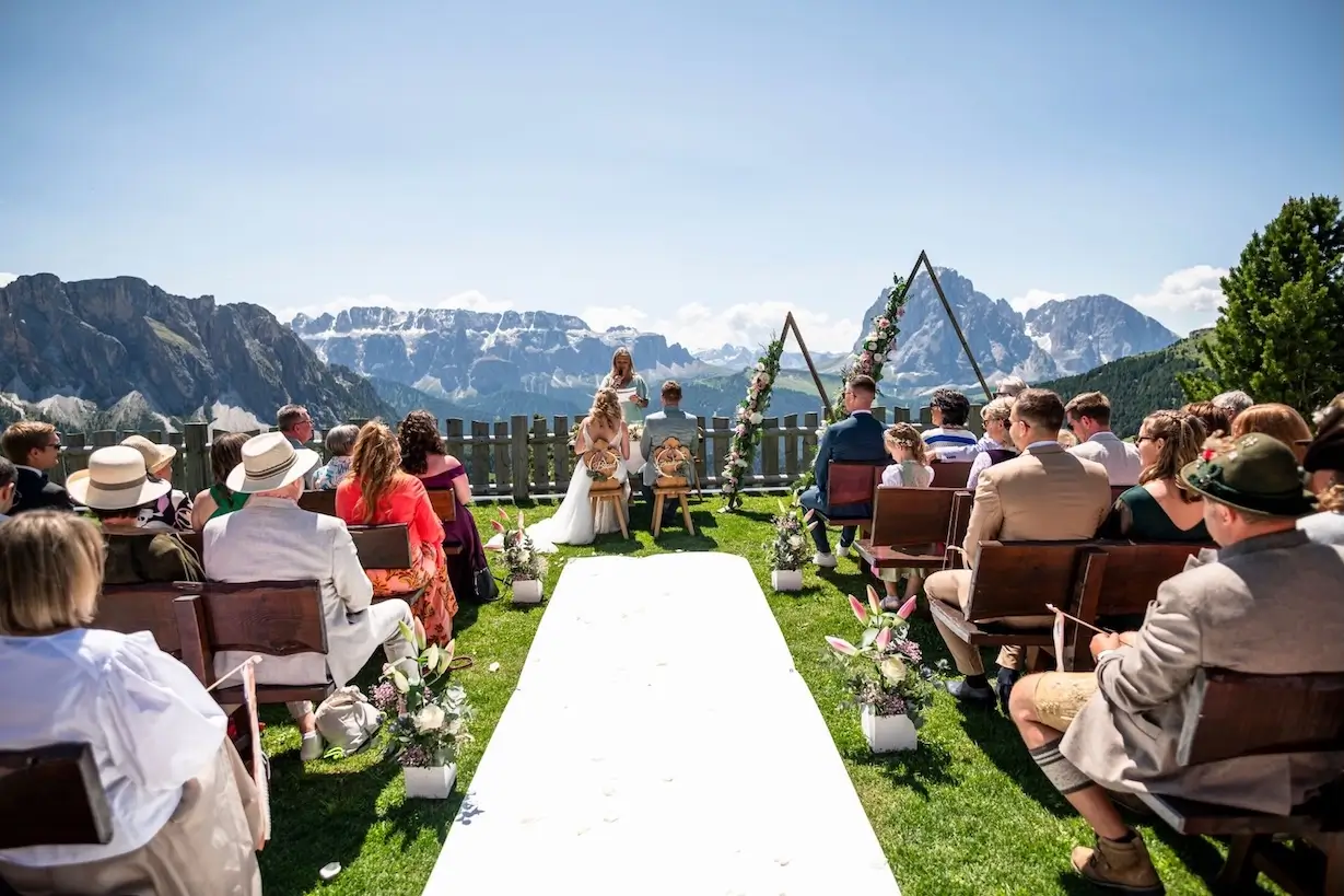 Gäste in Weiß beim Jawort am Meer stehen im Kreis und halten sich an den Händen