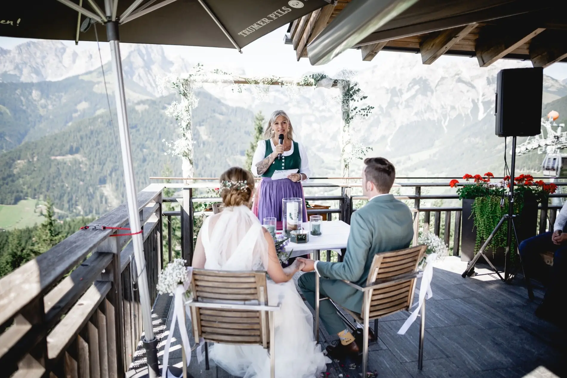 Naturkulisse vor Bergen mit Traurednerin Heike Schönbacher und Brautpaar auf Terrasse