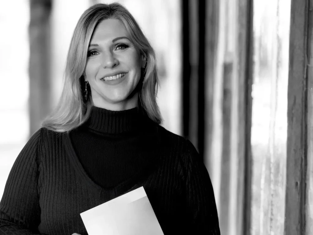 Heike Schönbacher, Trauerrednerin Graz, Profilbild mit Unterlagen in den Händen, schwarz-weiß